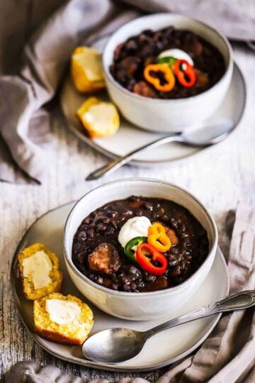 Two soup bowls filled with black bean and andouille soup.