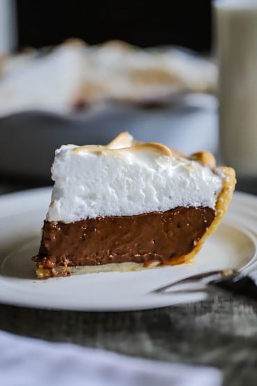 A side view of a slice of chocolate meringue pie on a dessert plate.