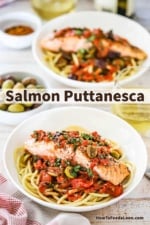 An overhead view of a two shallow pasta bowls each filled with a bed of bucatini pasta topped with salmon and a puttanesca sauce.