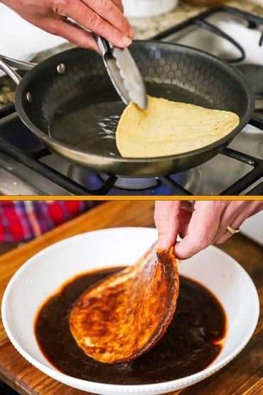 A person using a pair of metal tongs to turn a corn tortilla in a small skillet with hot oil and then coating that same tortilla in a bowl of enchilada sauce.