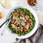 An overhead view of an individual white pasta bowl filled with spinach pasta with wild mushroom sauce.