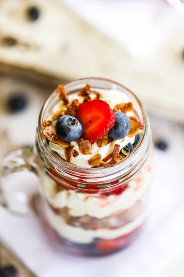 An overhead view of a glass jar holding a full serving of wild berry parfait with mascarpone.