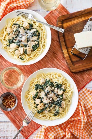 An overhead view of two pasta bowls filled with creamy chicken florentine both sitting on a bed of cooked pasta.