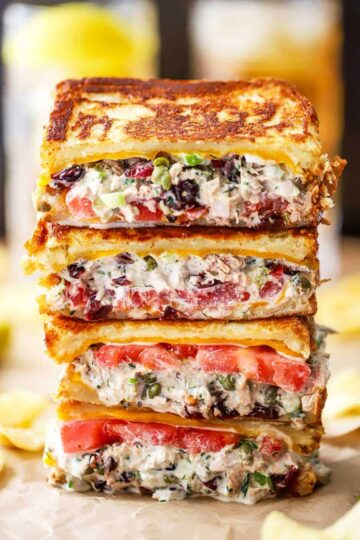 Four halves of tuna melt sandwiches that are stacked on top of each other with the interior of the sandwich visible.