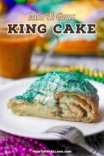 A close-up view of a slice of Mardi Gras King cake with glitter green icing on top and a circular cinnamon filling is visible.