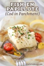 A close-up view of a steamed fillet of cod that has been cooked in a packet of parchment paper along with white wine, herbs, cherry tomatoes, and red onion.