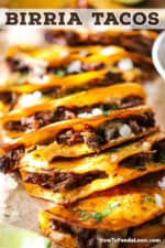 A straight-on view of a row of beef birria tacos that are in a row each one resting on top of the taco next to it and they are garnish with chopped onion and cilantro.