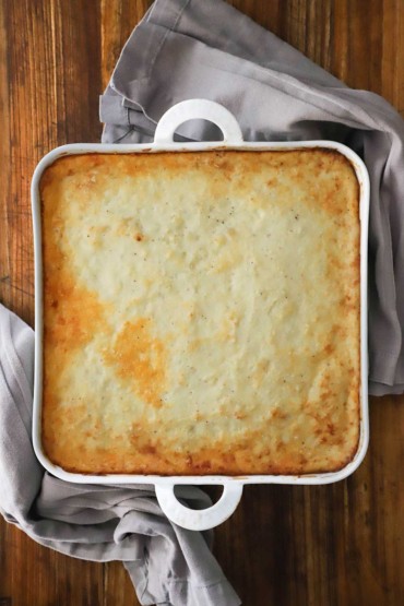 An overhead view of a square baking dish filled with a baked moussaka.