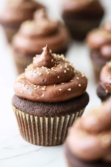 A view of several rows of chocolate cupcakes with marshmallow filling all sitting on a white marble slab.