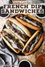 An overhead view of four large slow cooker French dip sandwiches with provolone cheese and several bowls of au jus sauce sitting nearby.