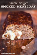 A straight-on view of a smoked meatloaf that has the end cut away and melty cheese on the inside of the loaf is visible and oozing down the front of the sliced loaf.