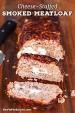 A straight-on view of a cheese-stuffed smoked meatloaf with several slices visible on a large wooden cutting board.
