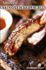 A person holding a single smoked St. Louis-style rib that has had homemade barbecue sauce brushed over the top of it.