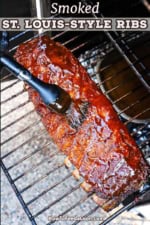 An overhead view of a rack of ribs that are resting on a rack in an electric smoker and are being brushed with BBQ sauce.