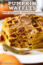 A close-up view a plate of pumpkin waffles with whipped cinnamon honey butter that have been partially eaten with a fork sitting on the plate in front of the waffles.