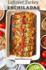 An overhead view of a rectangular white baking dish filled with leftover turkey enchiladas in an enchilada red sauce and topped with chopped lettuce and tomatoes.