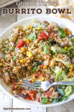 A close-up view of a white bowl filled with a turkey burrito bowl that has been stirred together and partially eaten with a fork inserted into the side.