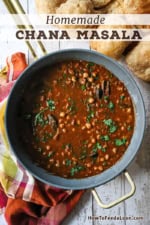 An overhead view of a large, deep skillet filled with chana masala with cooked chickpeas visible and chopped cilantro scattered on top.
