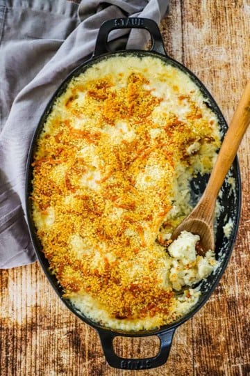 Creamy cauliflower gratin in an oval baking dish with some of it gone.