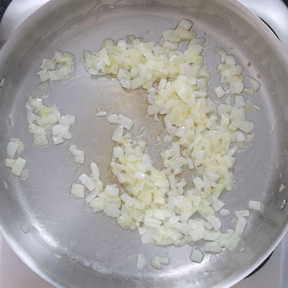 Chopped onions being sautéed in melted butter in a large skillet.