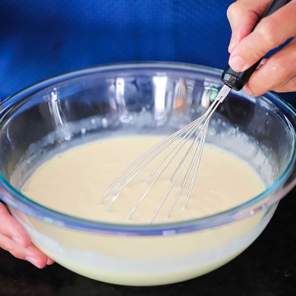 A person using a whisk to combine the liquid filling ingredients for easy key lime pie.