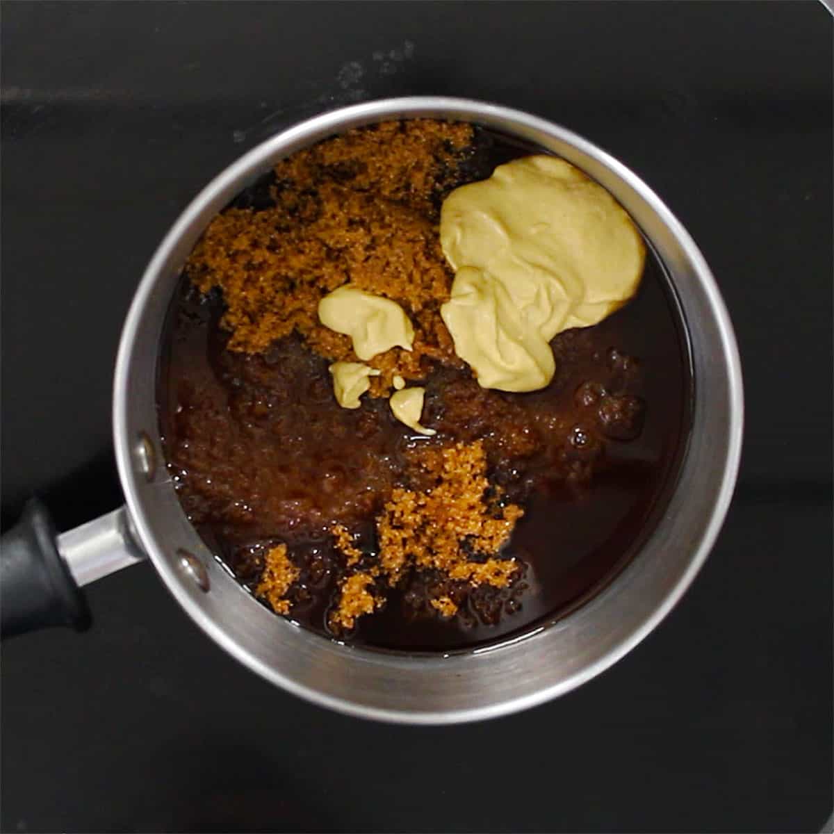 A saucepan filled with Dijon mustard, brown sugar, and apple cider vinegar.