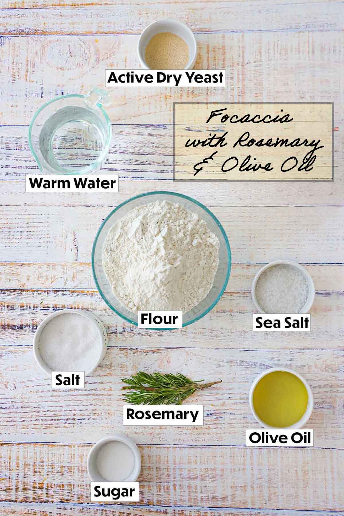 Ingredients for focaccia bread displayed on a white background, including all-purpose flour, fresh rosemary sprigs, olive oil, water, yeast, and salt, arranged neatly for easy preparation.