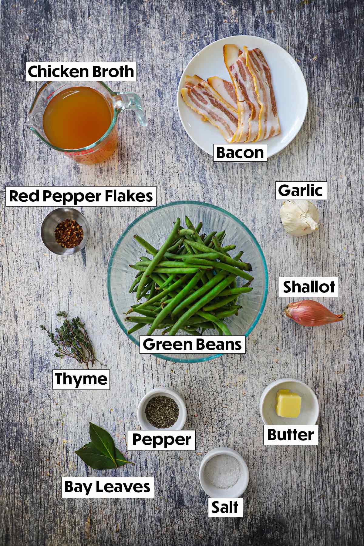 The ingredients for Southern-style green beans arranged on a wooden background, including fresh green beans, garlic cloves, diced onions, bacon, and seasonings, all neatly organized for easy preparation.
