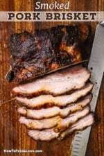 A sliced smoked brisket that is resting on cutting board with a large butcher's knife just underneath the meat.