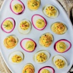 An assortment of deviled eggs in a white deviled egg tray.
