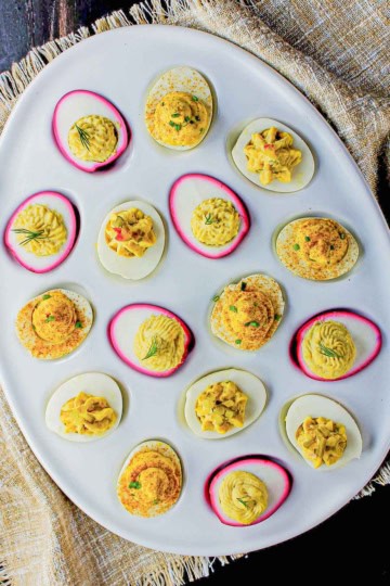 An assortment of deviled eggs in a white deviled egg tray.