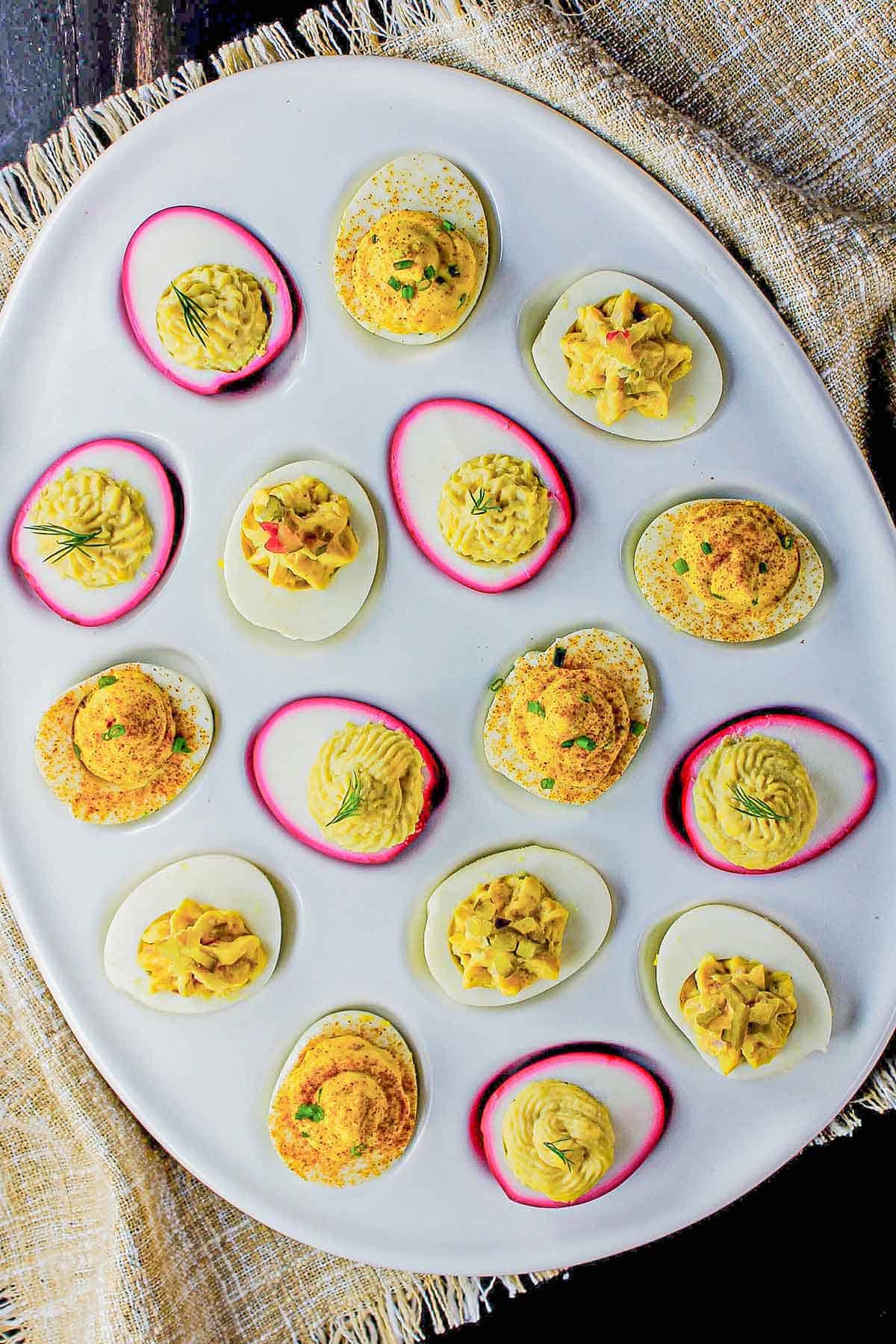 An assortment of deviled eggs in a white deviled egg tray. 