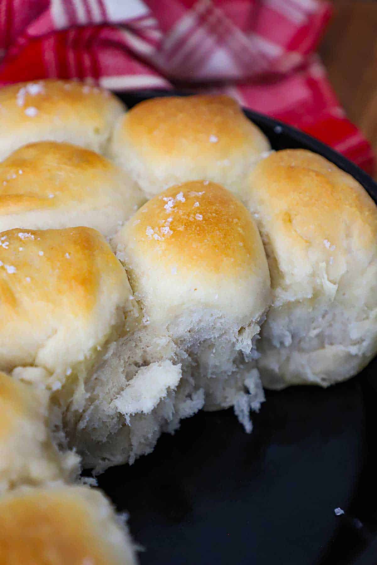 Fluffy freshly baked skillet dinner rolls with a few missing in a cast-iron skillet.
