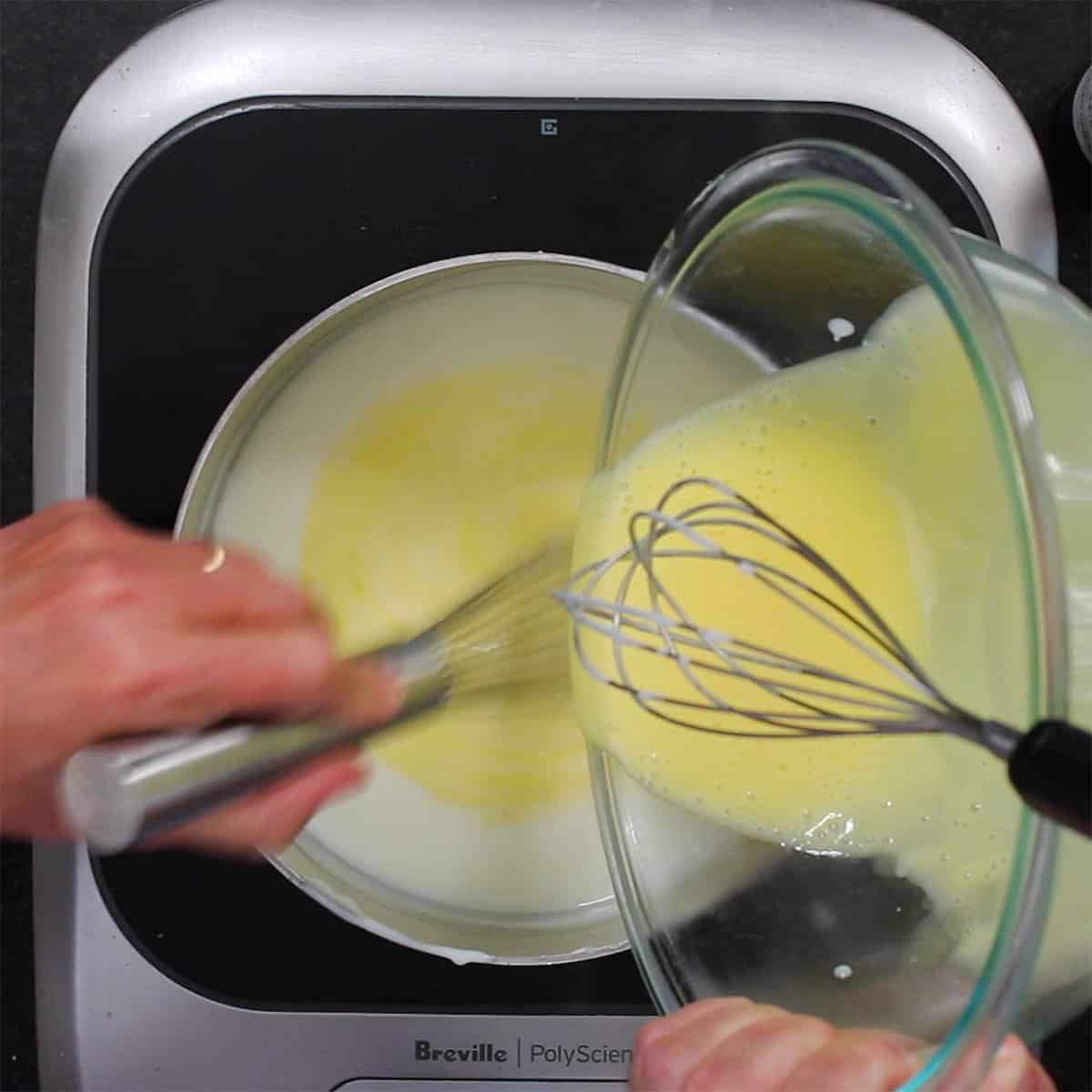 A person pouring tempered eggs and cream into a saucepan filled with more hot cream.