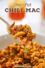 A fork being used to lift a bite of one-pot chili mac from a bowl filled with chili mac
