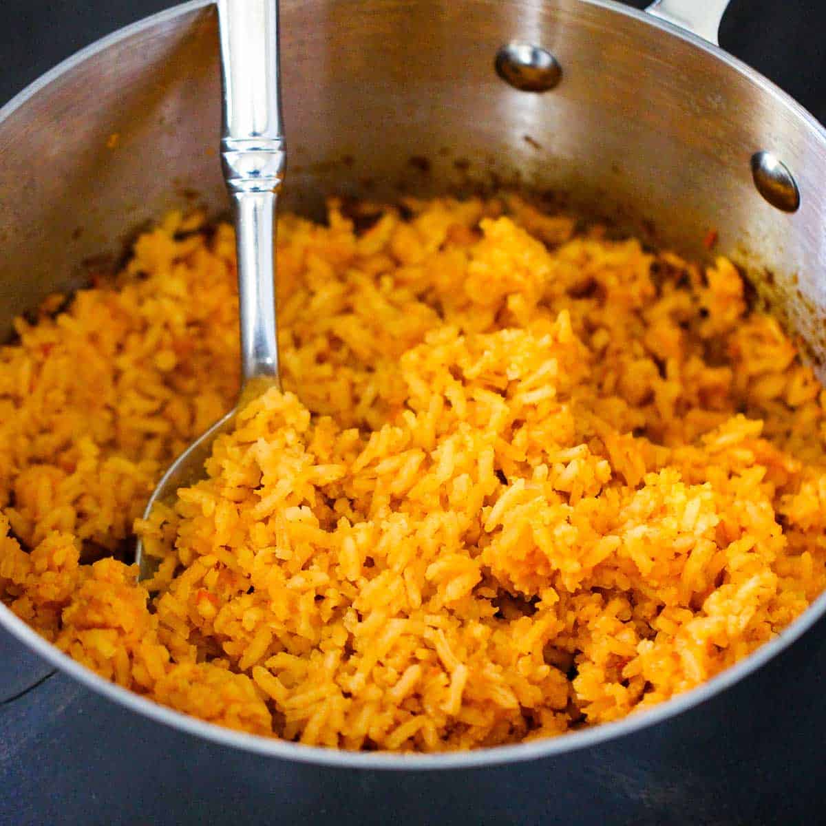 A person submerged in a saucepan filled with homemade Mexican rice.