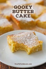 A square slice of an Gooey Butter Cake with a bite taken out it sitting on a white dessert plate.