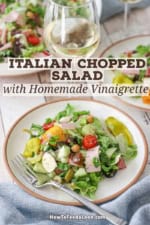 A salad plate filled with Italian chopped salad with homemade vinaigrette sitting next to a glass of white wine.