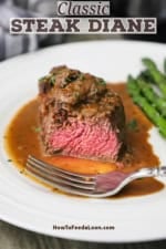 A serving of classic steak Diane that has been cut open revealing a bright pink center with the steak resting in a brown mushroom sauce.