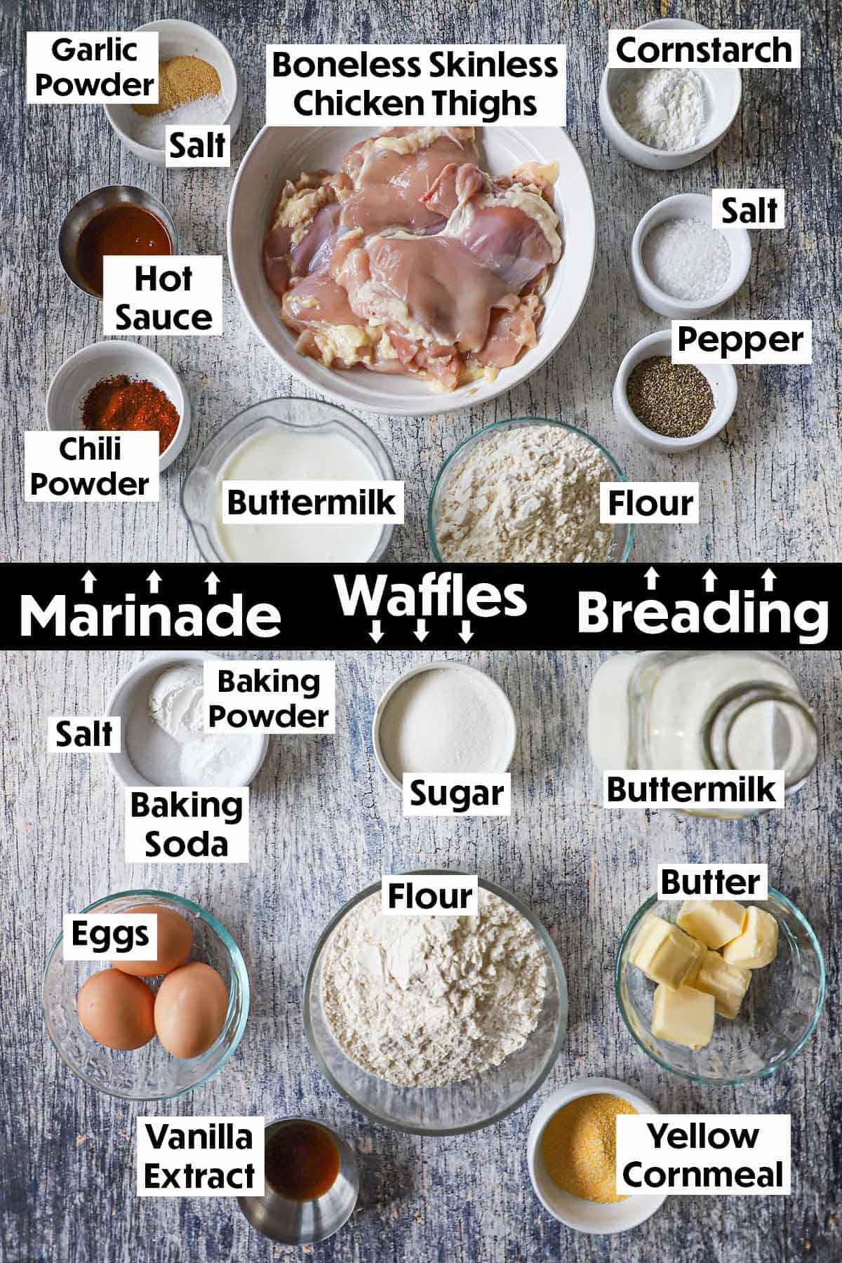 An arrangement of ingredients for crispy chicken and waffles on a wooden grey background including chicken, buttermilk, seasonings, flour, eggs, butte, sugar, and vanilla extract.