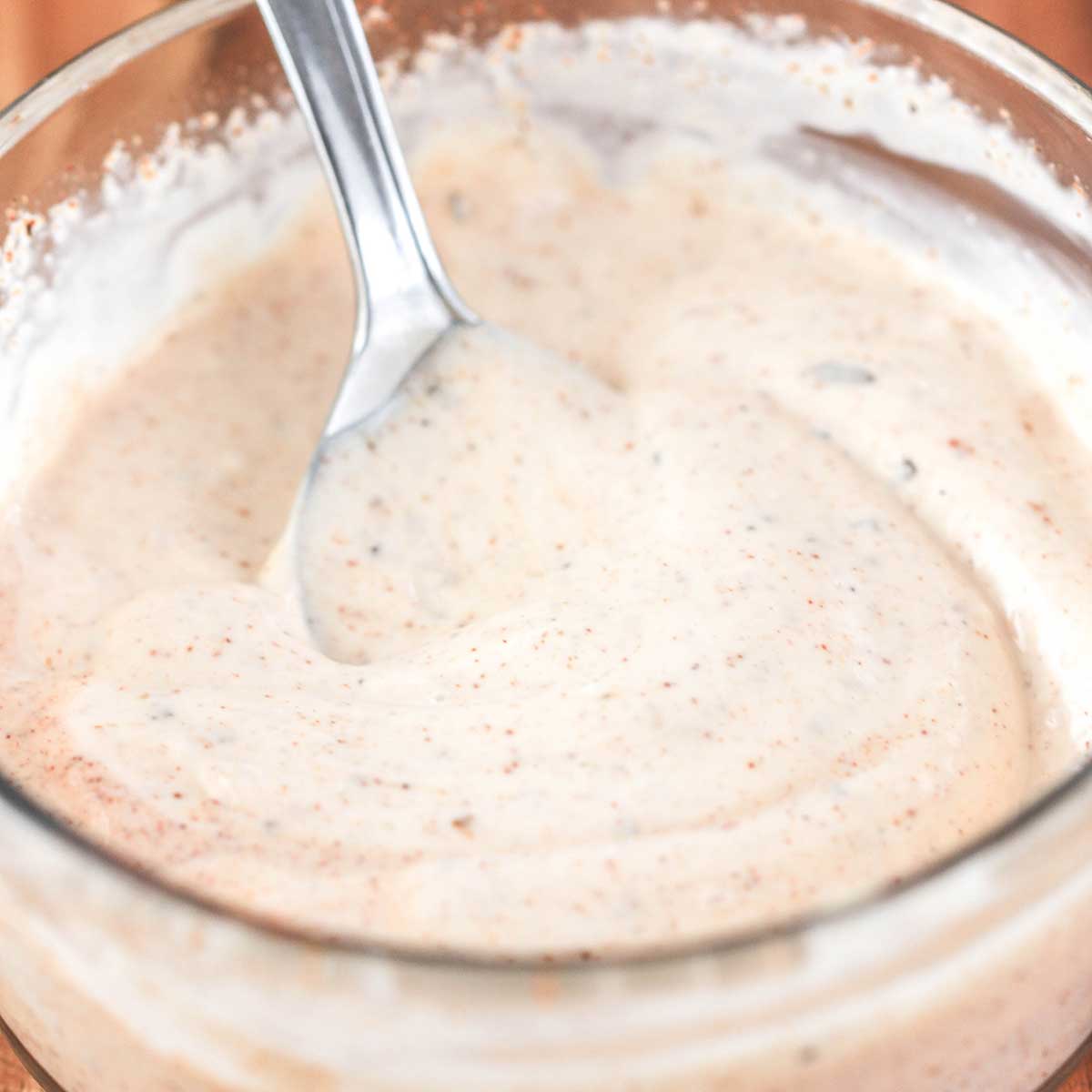 A close-up view of a Cajun mayonnaise mixture in a small glass bowl.