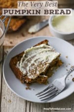 A half eaten slice of best homemade pumpkin bread with softened butter smeared on the top and is resting on a small white plate.