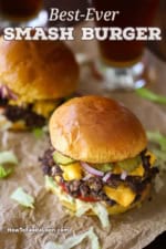 Two double-stacked smash burgers that are garnished with lettuce, tomato, cheese, pickles, and burger sauce.