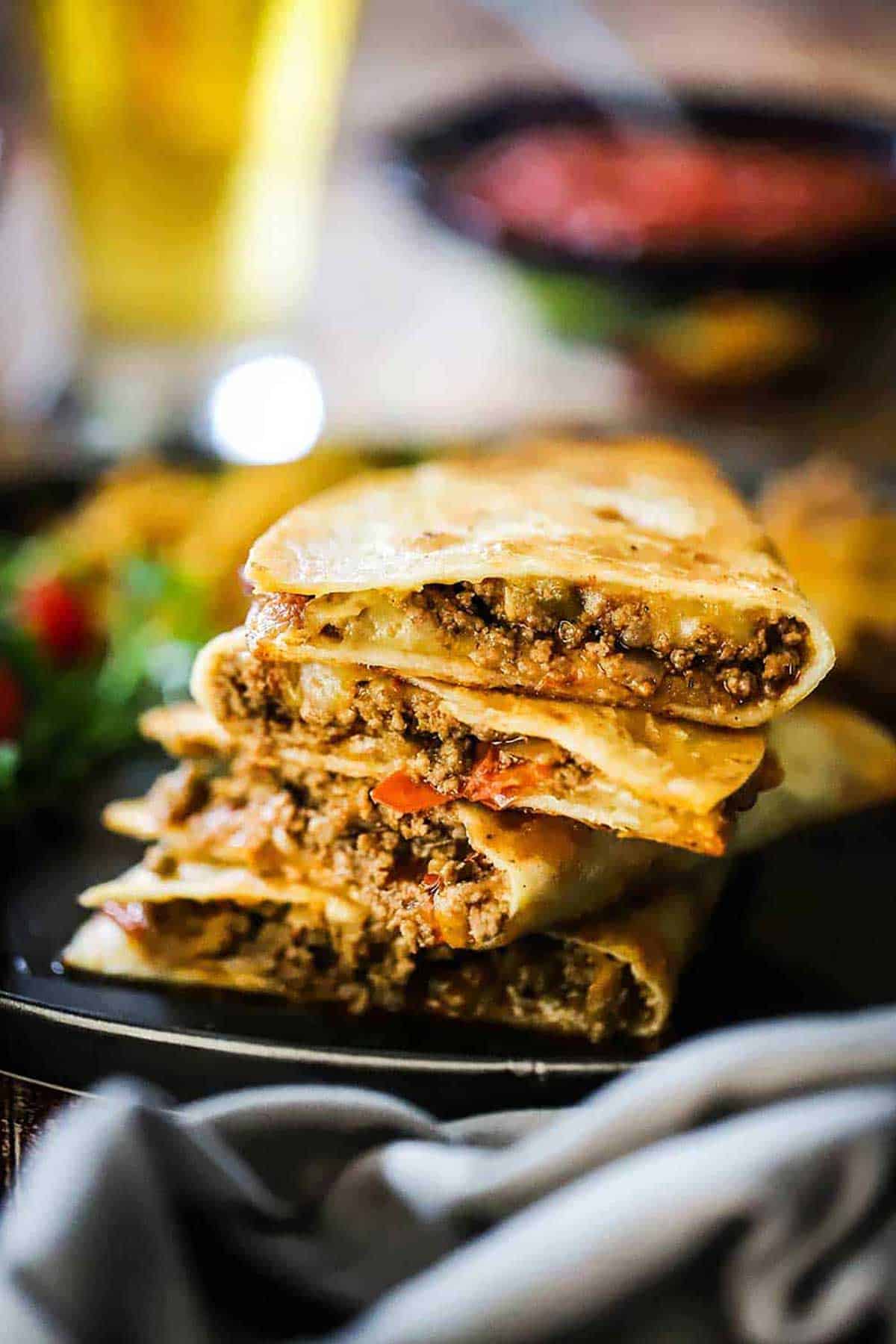 A stack of four taco quesadillas that have been cut in half so the meat filling is visible.