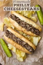An overhead view of two homemade Philly cheesesteaks sitting next to each other on brown sandwich paper.