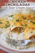 A partially eaten chicken enchilada with sour cream sauce.