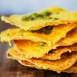A close-up view of a stack of classic nachos topped with chopped jalapeños.