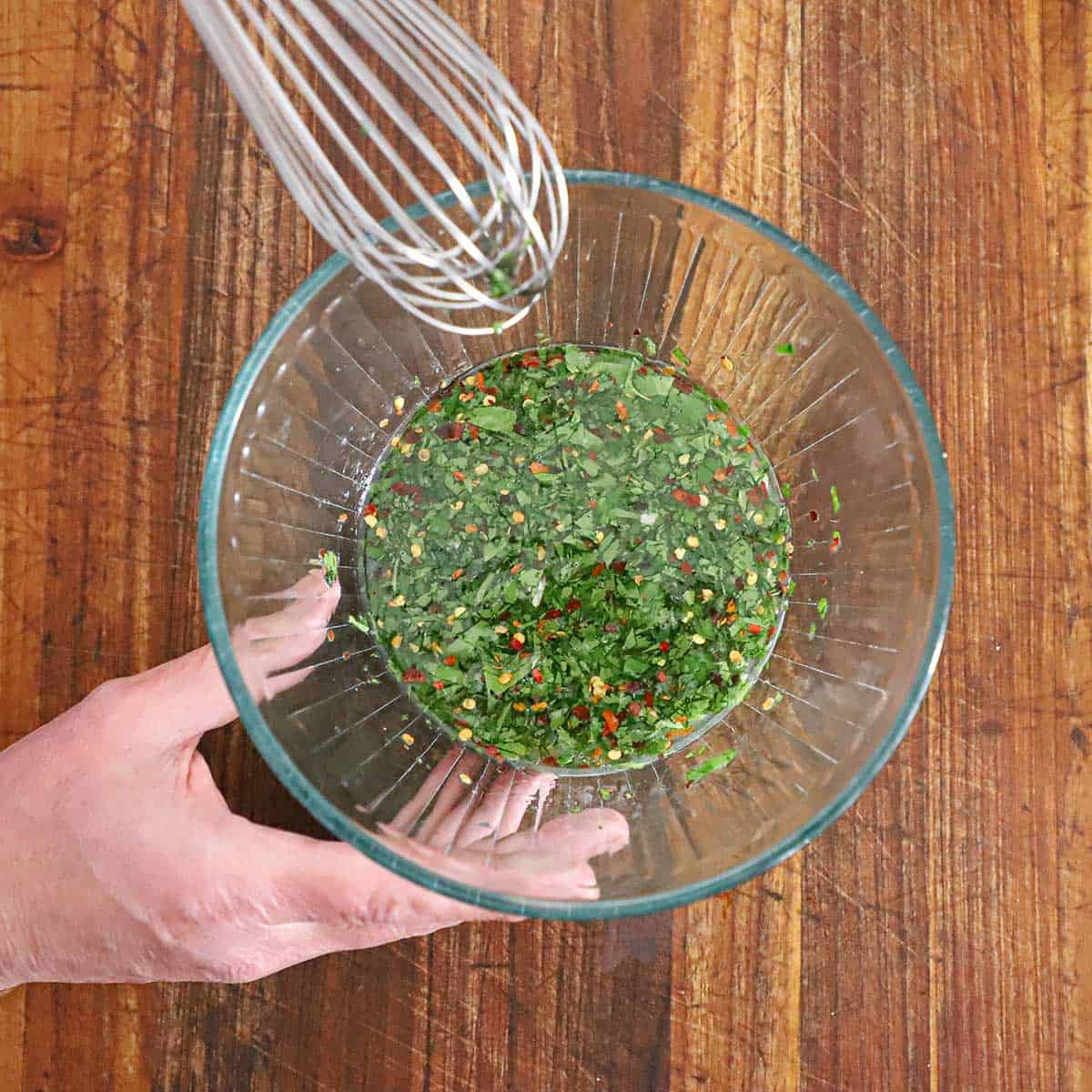 A person using a whisk to mix the marinade for a steak fajita quesadilla.